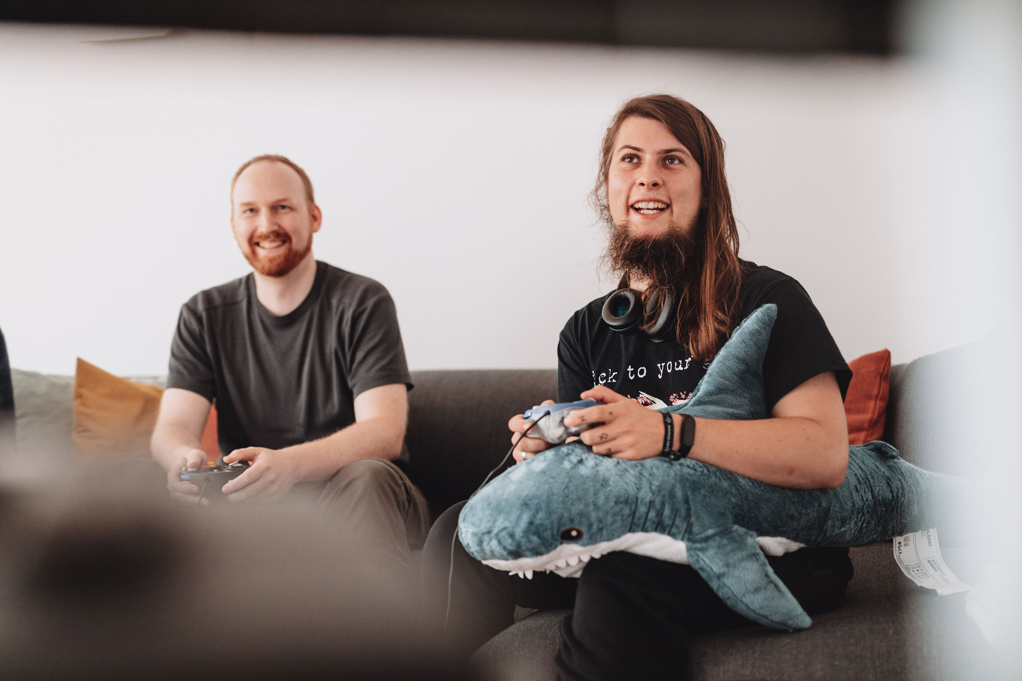 Zwei Männer sitzen auf einem Sofa und spielen ein Computerspiel