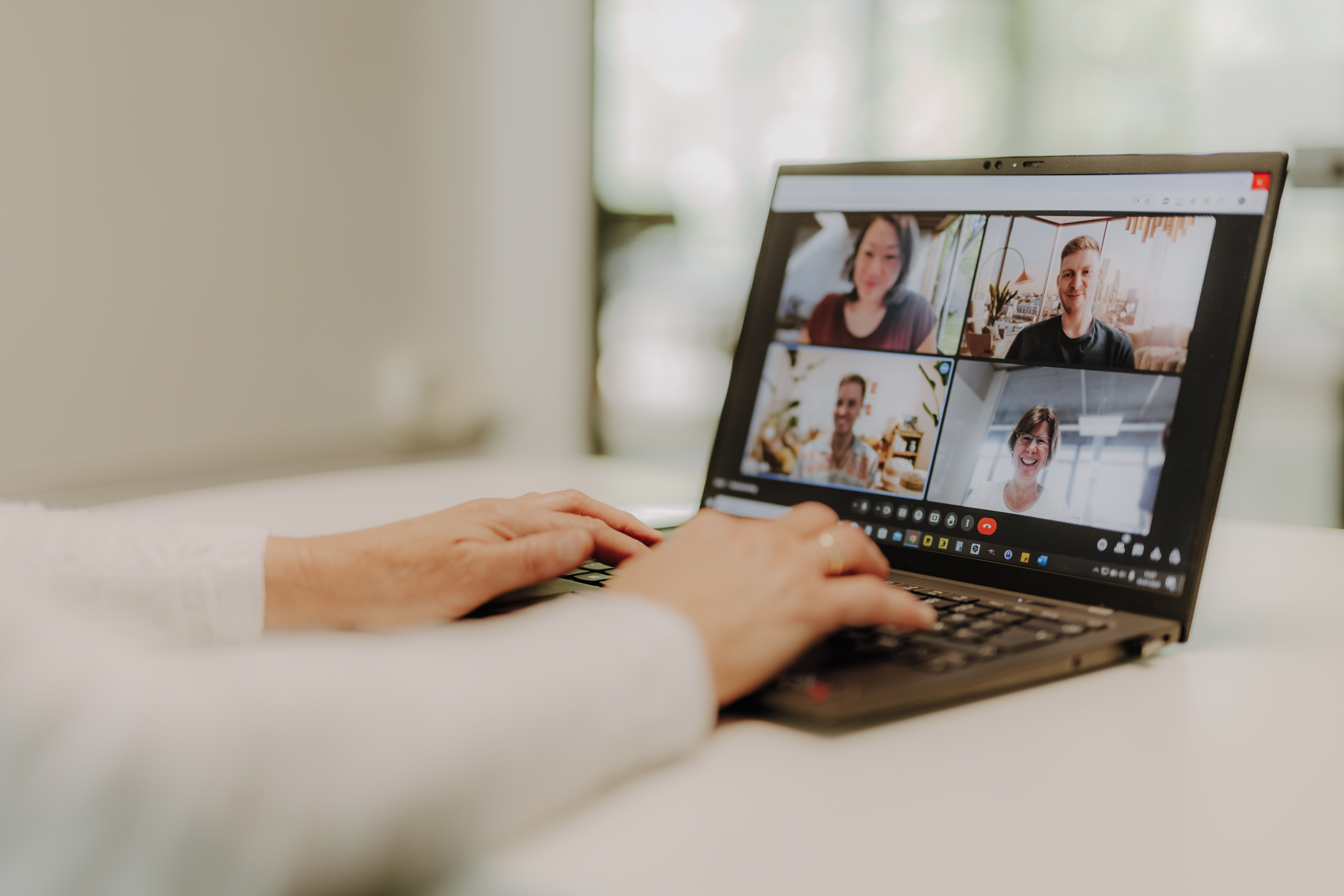 Laptopbildschirm mit 4 lächelnden Personen in einer Videokonferenz