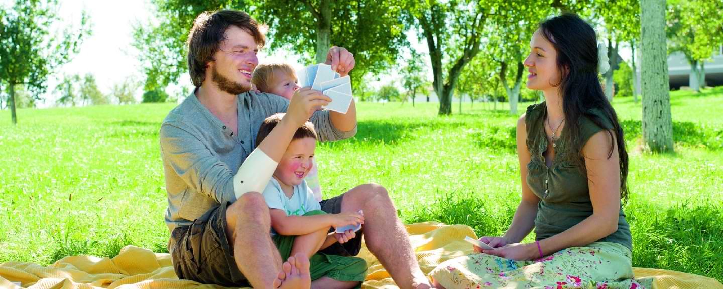 Eine Familie sitzt auf einer Wiese und spielt Karten