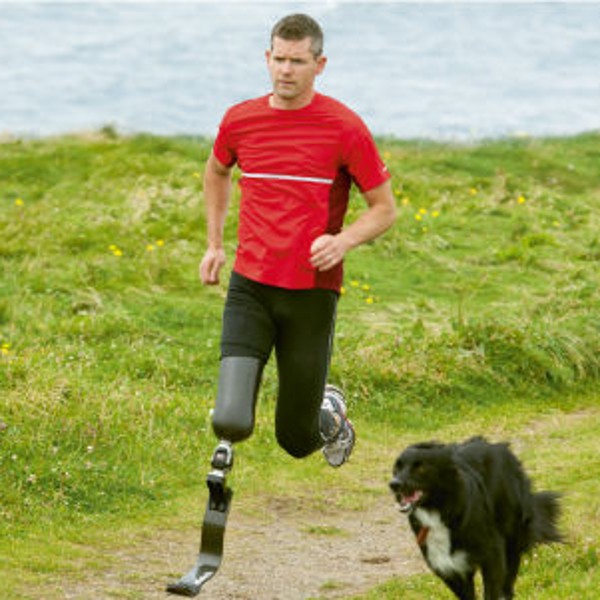 Ein Mann mit einer Beinprothese joggt mit einem Hund