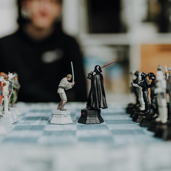 Ein Star Wars Schachspiel, im Hintergrund sieht ein junger Mann dem Spiel zu