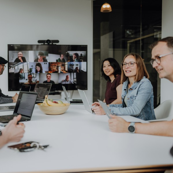 Mitarbeiter sitzen im Büro und remote zusammen